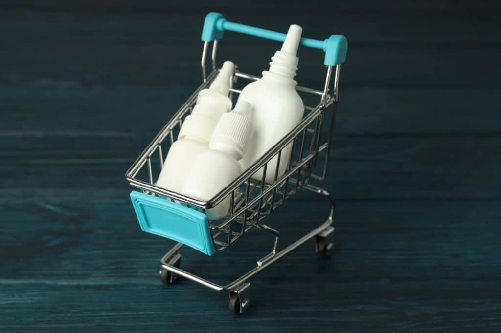 Shop trolley with bottles of nasal spray on wooden background