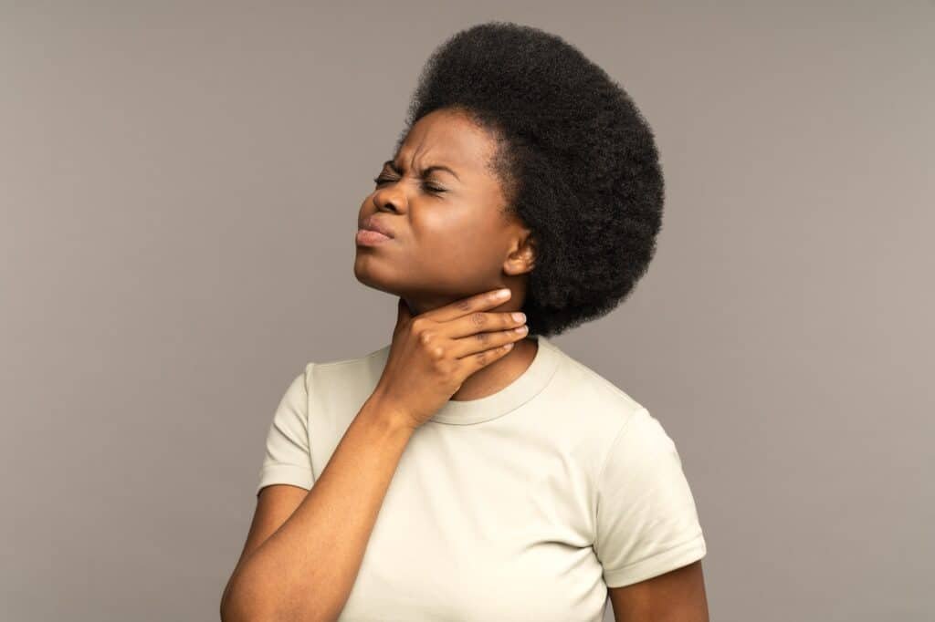 Afro woman having sore throat, tonsillitis, suffering from painful swallowing, strong pain in throat