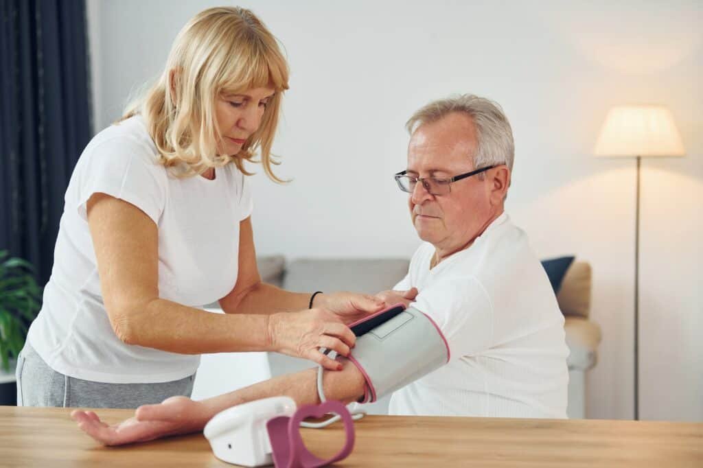 Wife measuring blood preasure of her husband. Senior man and woman is together at home