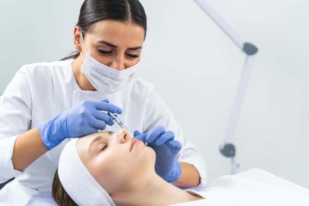 Dermatologist injecting a cheek filler to a woman