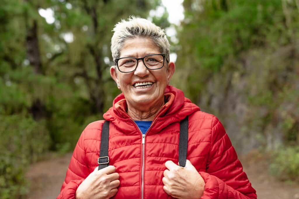Happy senior woman having during trekking activities day in the wood