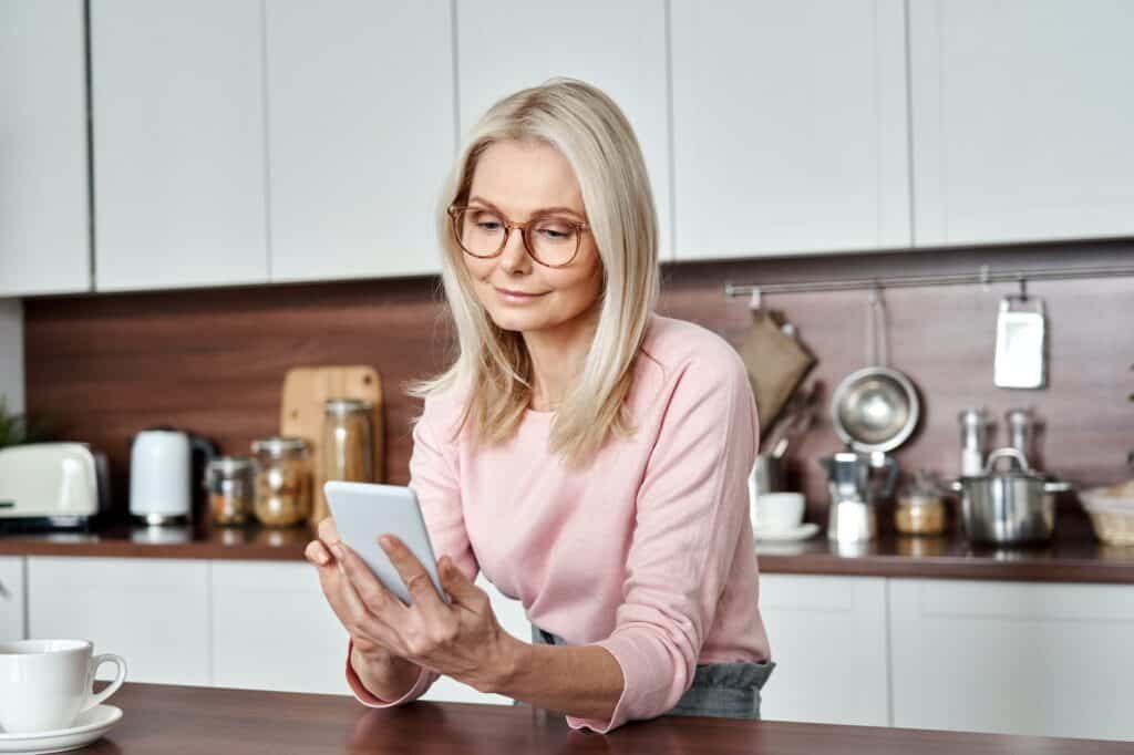 Middle aged 50 years old woman using smartphone at home.
