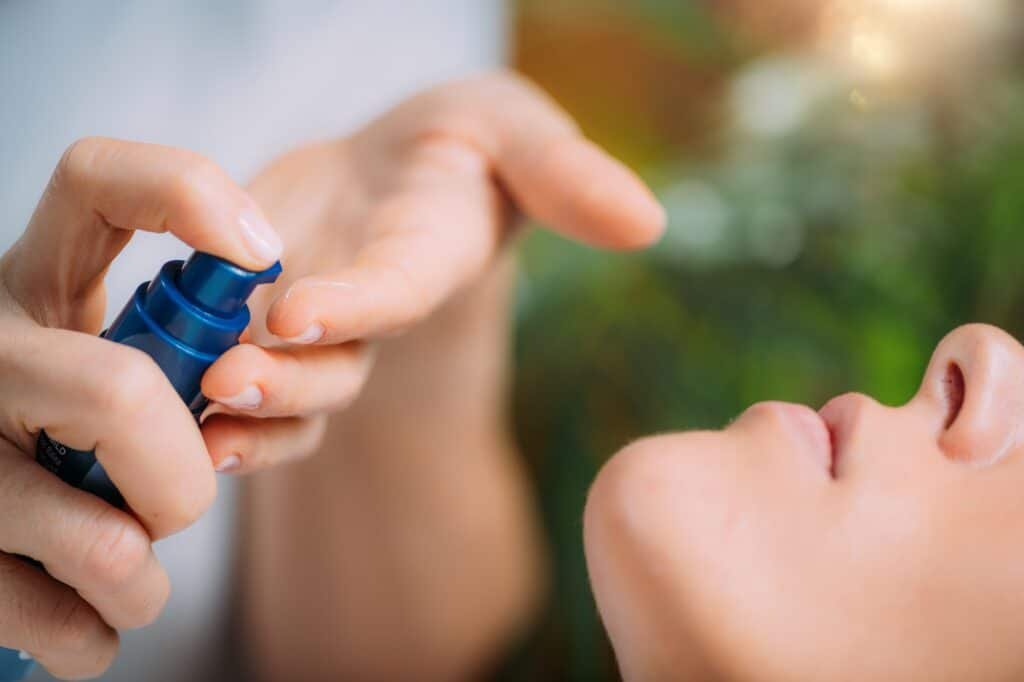 Retinol Treatment. Cosmetician Applying Retinol Serum on Woman’s Face