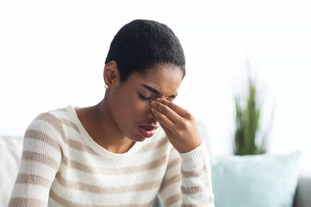 Sinusitis Concept. Sick Young Black Woman Touching Her Nose Bridge At Home