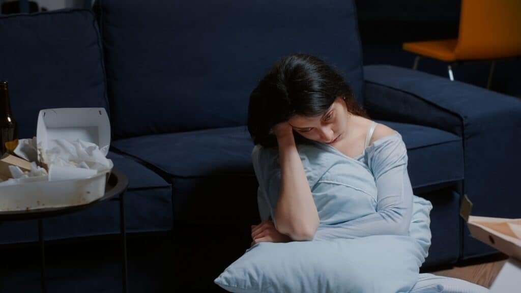 Unhappy woman sitting on floor thinking at problems, suffering from anxiety