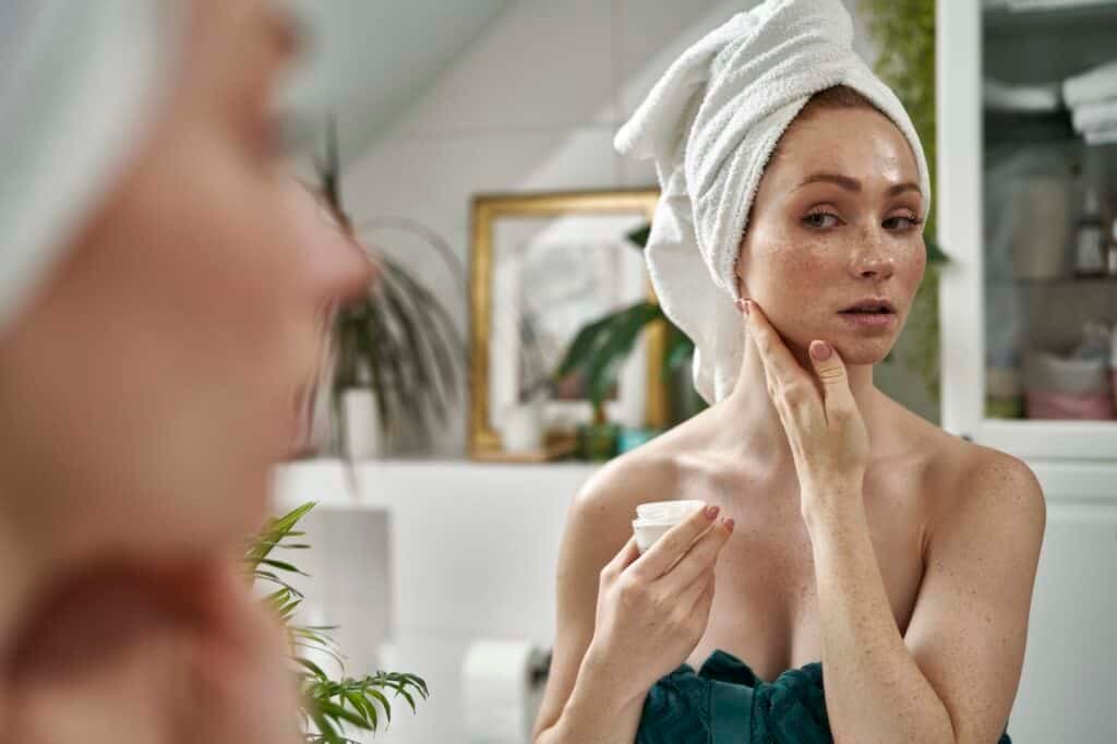 Woman using face cream after the shower in the bathroom