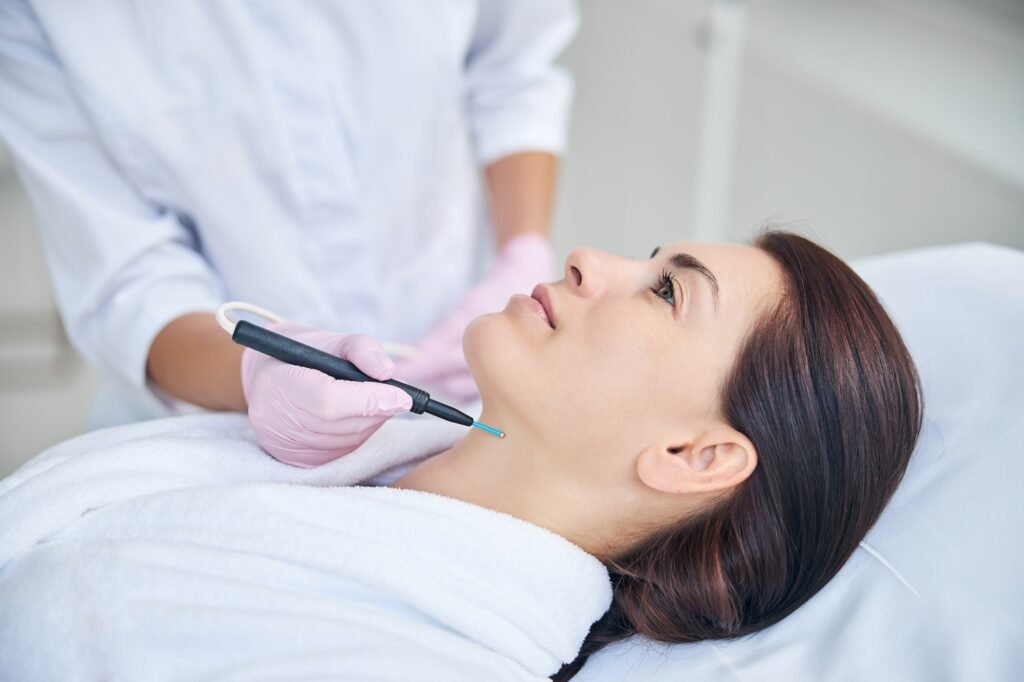 Doctor removing a red mole on the patient skin