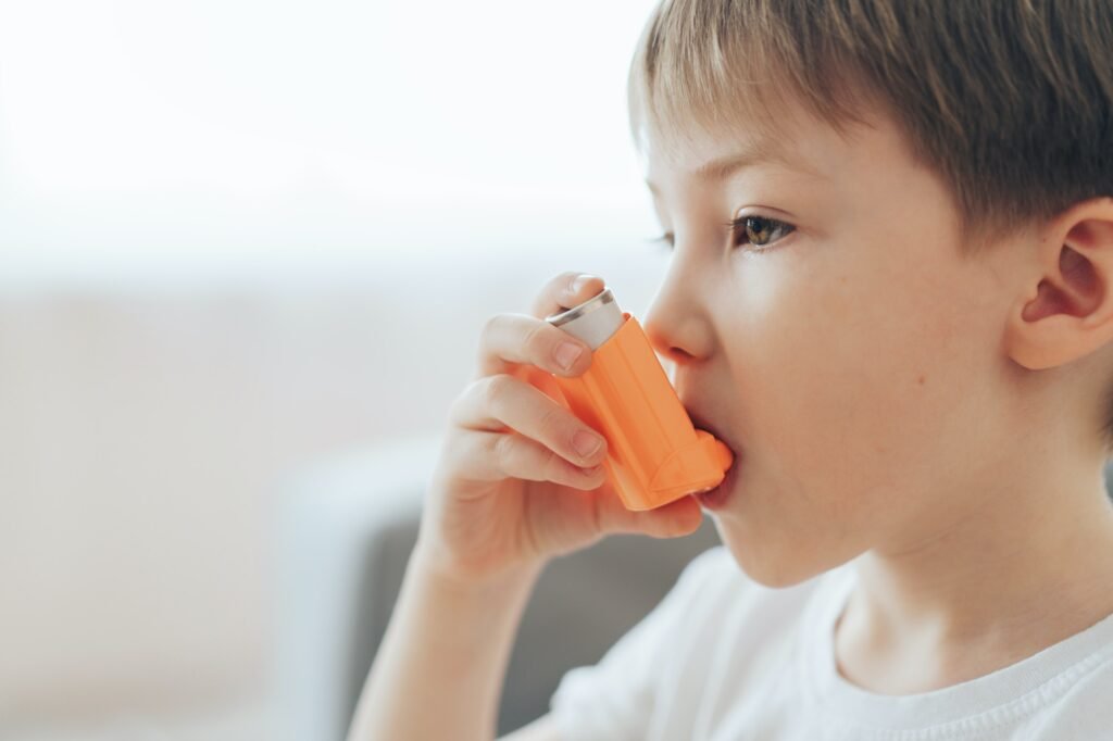 En liten gutt inhalerer medisin gjennom en astmainhalator