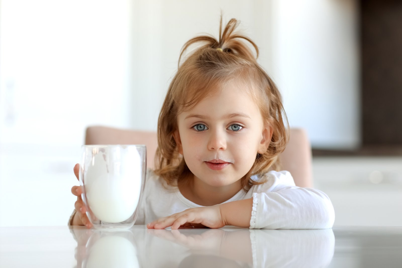 child girl with mustache of milk on lips holding glass of milk dairy,calcium for good kids health
