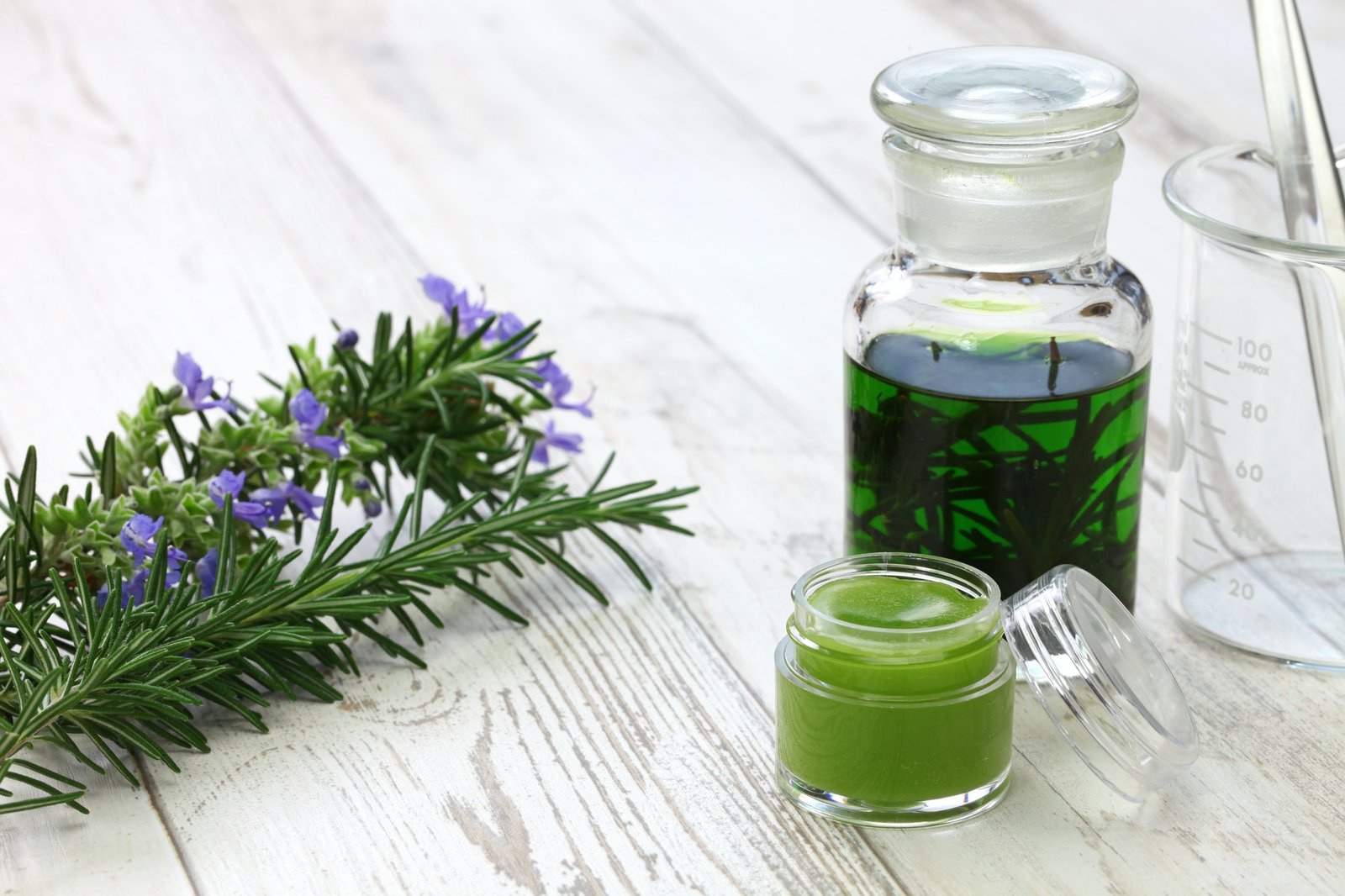 Homemade rosemary balm and ingredients and tools to make it.