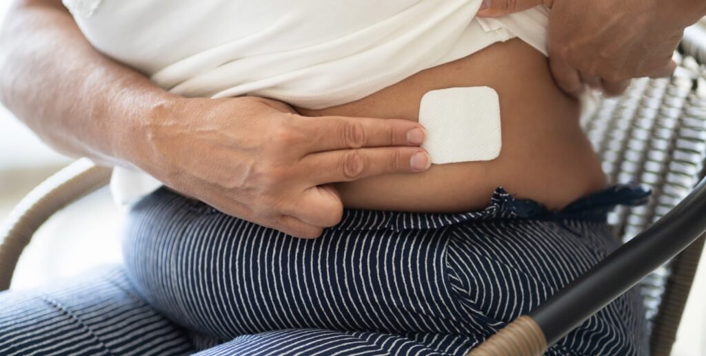 Bilde av dame som sitter og har tatt på østrogenplaster.